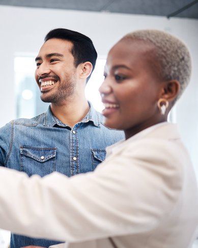 Ein Mann und eine Frau arbeiten gemeinsam an einem Whiteboard, während sie bunte Haftnotizen anbringen und Ideen austauschen.