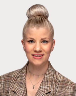 Eine Person mit blonden Haaren im Dutt trägt einen karierten Blazer und lächelt in die Kamera. Der Hintergrund ist neutral.