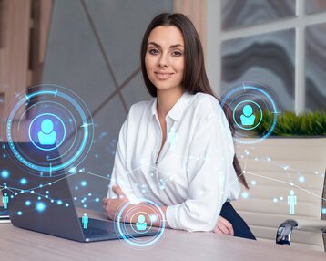Eine Frau sitzt an einem Schreibtisch mit einem Laptop, umgeben von digitalen Symbolen, die Vernetzung und Kommunikation darstellen.