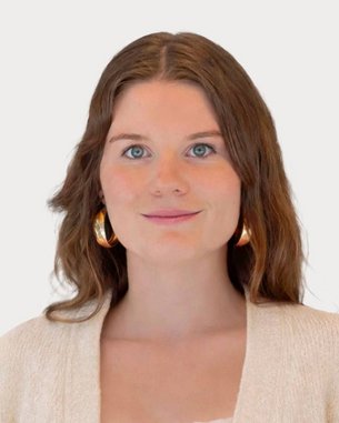 Junge Frau mit langen, braunen Haaren und großen Ohrringen, trägt einen hellen Pullover und schaut direkt in die Kamera.